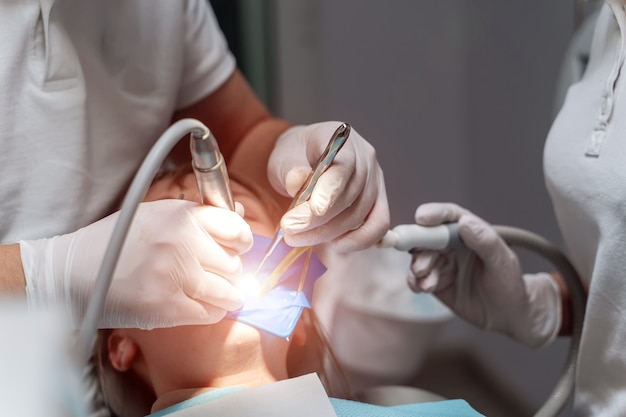 Dois dentistas examinam os dentes do paciente para o tratamento posterior