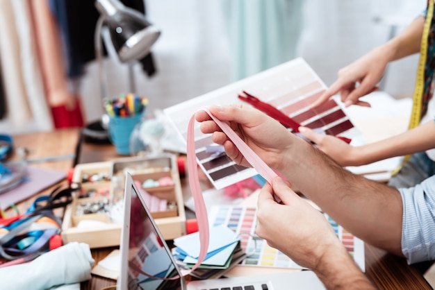 Dois desenhadores de moda que olham a paleta de cores.