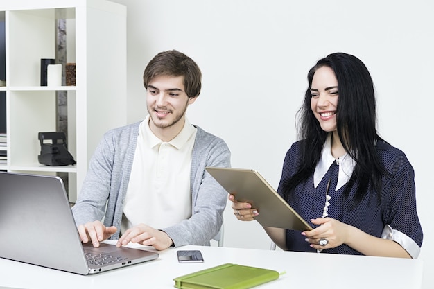 Dois designers casuais sorridentes, trabalhando com laptop e tablet no escritório. Trabalho de equipe wooman do homem.