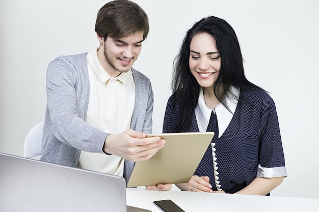 Dois designers casuais sorridentes, trabalhando com laptop e tablet no escritório. Trabalho de equipe wooman do homem.