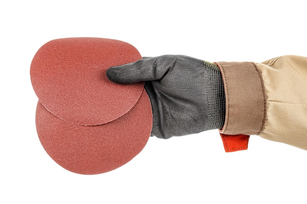 Foto dois discos de lixa para lixar na mão do trabalhador em uma luva protetora preta isolada no branco