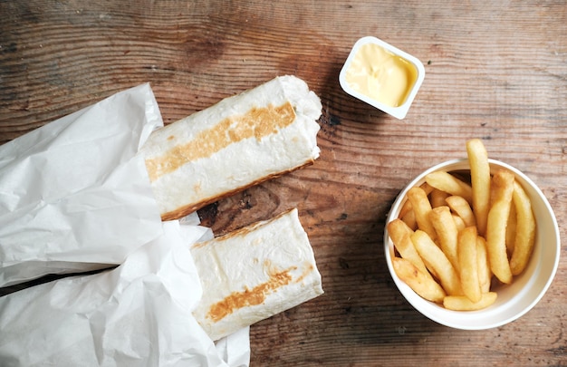 Dois doadores e batatas fritas com molho de queijo em uma vista superior de fundo de madeira shawarma em uma mesa de madeira entrega de alimentos