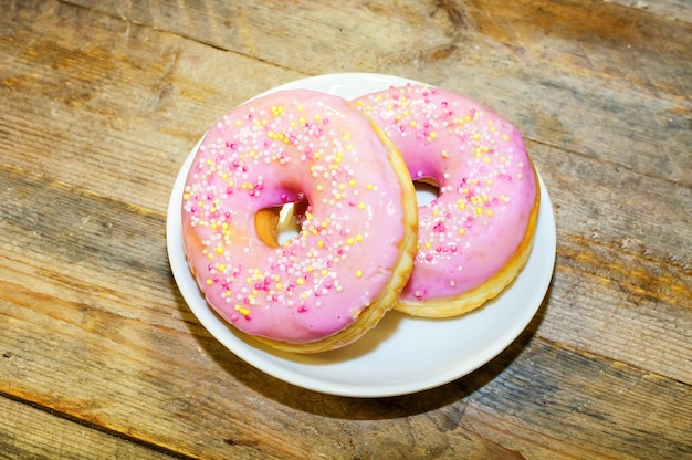 Dois donuts doces com cobertura rosa e salpicaduras