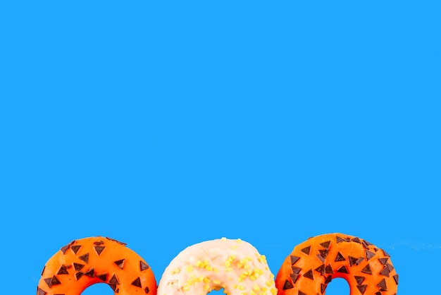 Dois donuts laranja e um branco sobre fundo azul Espaço para fotos de texto de alta qualidade