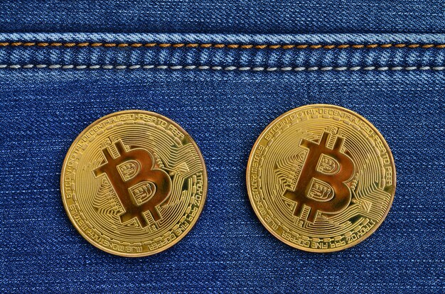 Dois dourados Bitcoins é mentiras em um tecido jeans azul