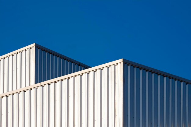 Dois edifícios industriais de aço ondulado contra o fundo do céu azul claro