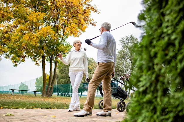 Foto dois elegantes jogadores de golfe sênior jogando golfe juntos e aproveitando o tempo livre na aposentadoria.