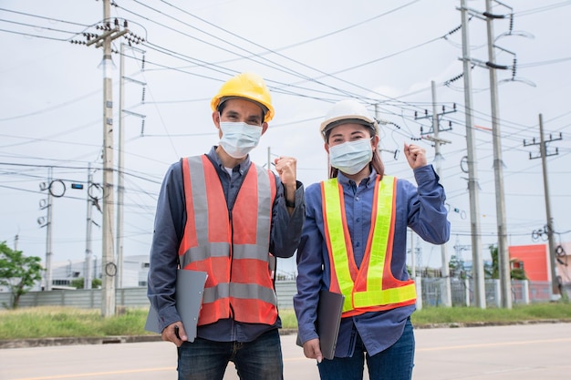 Dois eletricistas asiáticos na estação de sistema de energia de inspeção de serviço no local