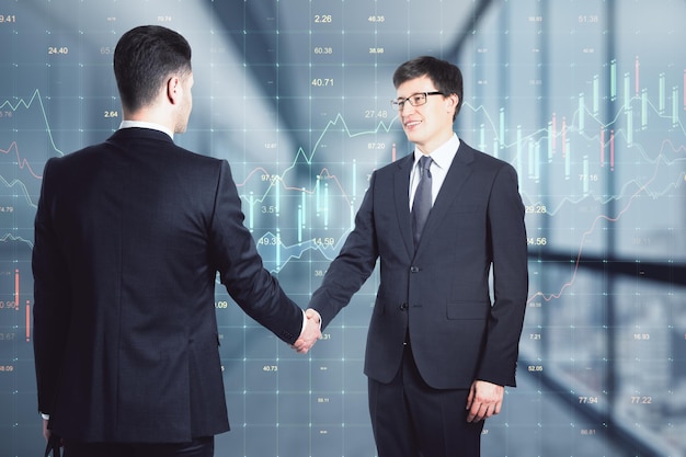Dois empresários apertando as mãos negociando gráficos em segundo plano Acordo e conceito de acordo