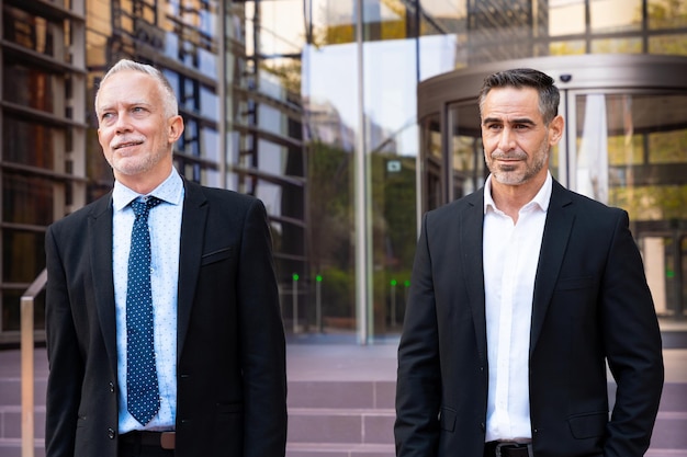 Foto dois empresários atraentes e confiantes caminhando pelas ruas da cidade.