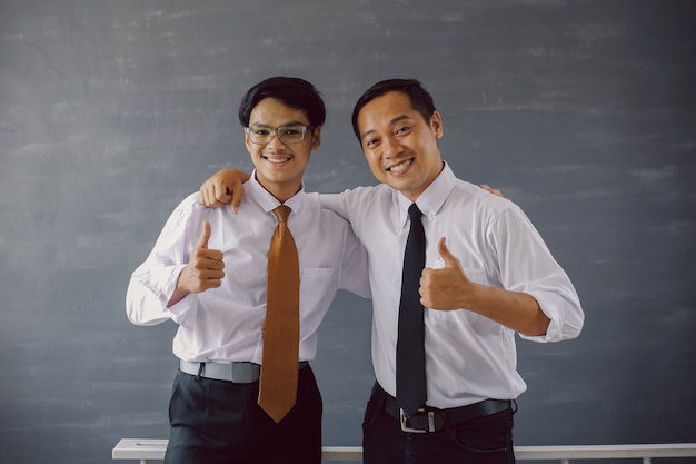 Dois empresários de camisa e gravata sorrindo enquanto se abraçam e entregam o polegar para a câmera