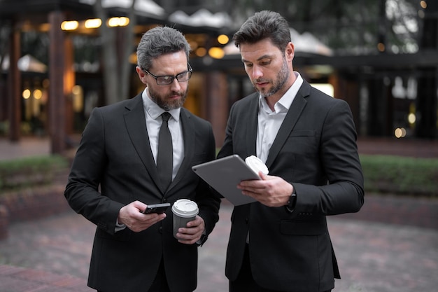 Dois empresários discutindo o uso de tablet na pausa para o café ao ar livre, dois empresários conversam sobre o projeto