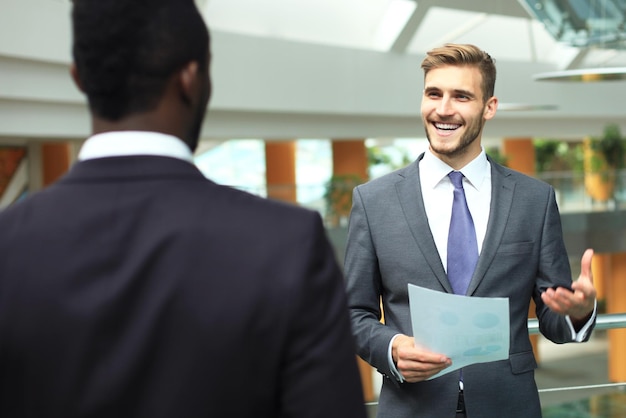 Dois empresários jovens multinacionais discutindo negócios em reunião no escritório.