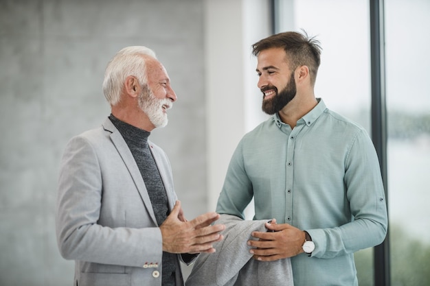 Dois empresários sorridentes andando e conversando em um escritório moderno.