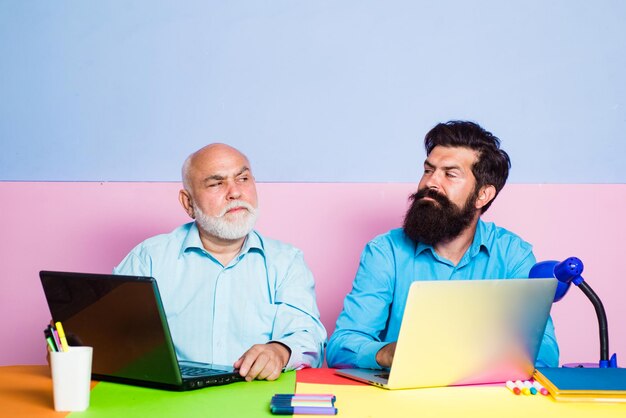 Dois empresários trabalhando no local de trabalho empresários usando laptop no trabalho duas gerações diferentes idades...