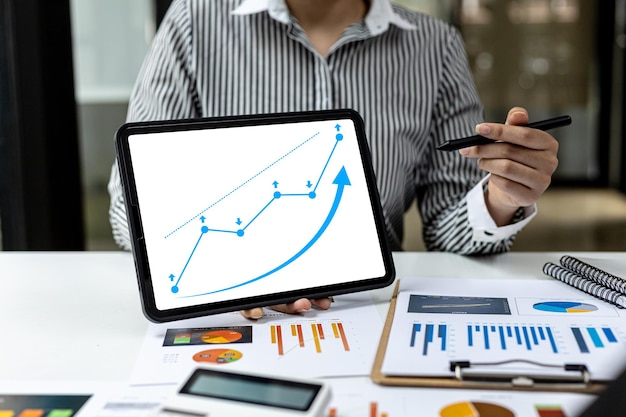 Dois empresários usando um tablet para visualizar os relatórios financeiros da empresa, gráficos que mostram dados financeiros e numéricos de crescimento. O conceito de gestão financeira para crescer e ser lucrativo.