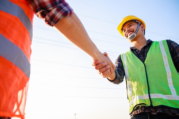 Dois engenheiros apertando as mãos no canteiro de obras ao pôr do sol Conceito de aperto de mão de negócios