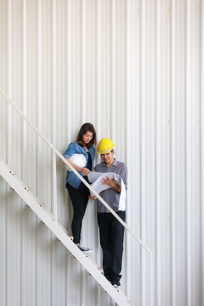 Dois engenheiros asiáticos, homem e mulher, discutindo no canteiro de obras