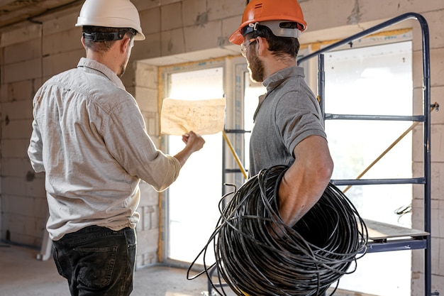 Dois engenheiros construtores conversando no canteiro de obras, um engenheiro explicando um desenho a um trabalhador.