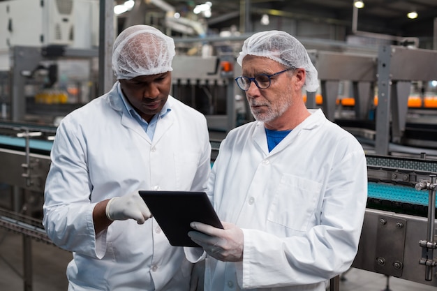 Foto dois engenheiros de fábrica discutindo sobre tablet digital