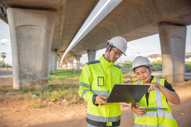 Dois engenheiros discutem sobre o trabalho no local da grande ponte em construçãogestão consultando pessoas discussão com engenheiros sobre o progresso e planejamento de construção da rodovia