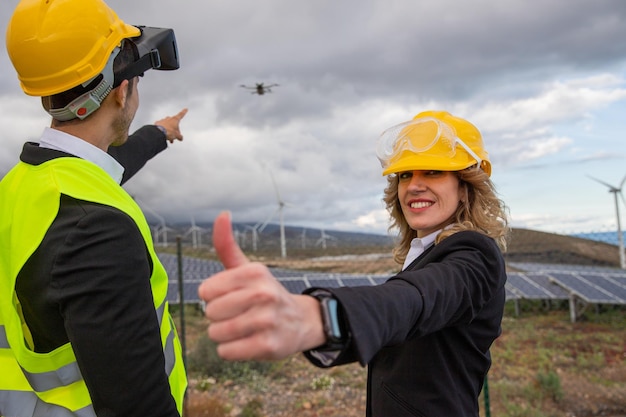 Dois engenheiros durante uma inspeção com drone e fones de ouvido VR em uma expressão satisfeita de fazenda solar