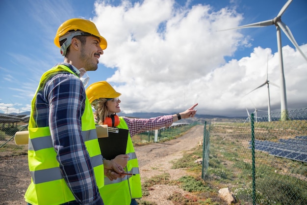 Dois engenheiros estão conversando enquanto observam o conceito de energia renovável de turbinas eólicas