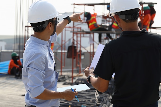 Foto dois engenheiros trabalham no canteiro de obras. eles estão verificando o andamento do trabalho.