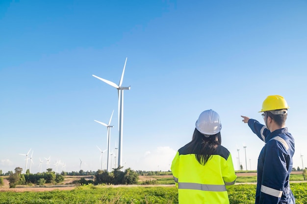 Dois engenheiros trabalhando e segurando o relatório na estação geradora de energia do parque de turbinas eólicas na montanhaTailândia pessoasTécnico homem e mulher discutem sobre o trabalho