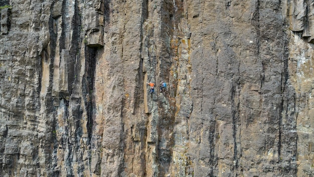 Dois escaladores praticando montanhismo em parede de pedra vertical