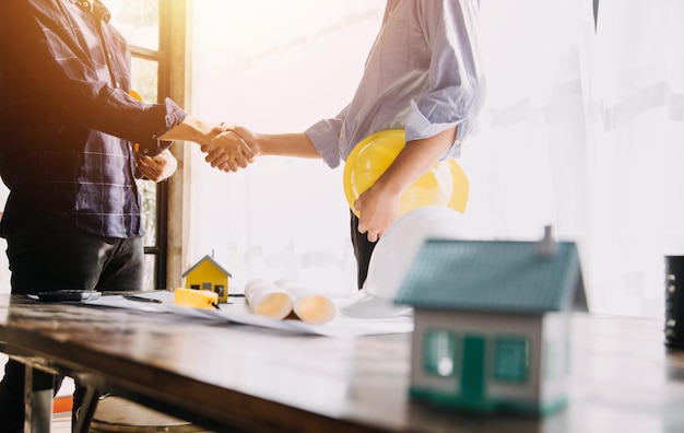 Dois especialistas inspecionam o projeto imobiliário do canteiro de obras do edifício industrial comercial com o investidor do engenheiro civil usam o laptop no fundo guindaste arranha-céu estruturas de concreto cofragem