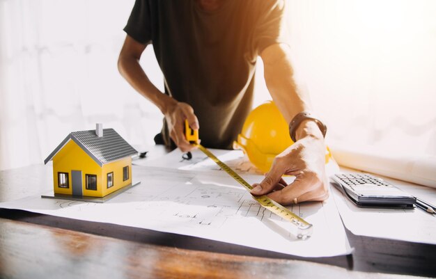 Dois especialistas inspecionam o projeto imobiliário do canteiro de obras do edifício industrial comercial com o investidor do engenheiro civil usam o laptop no fundo guindaste arranha-céu estruturas de concreto cofragem