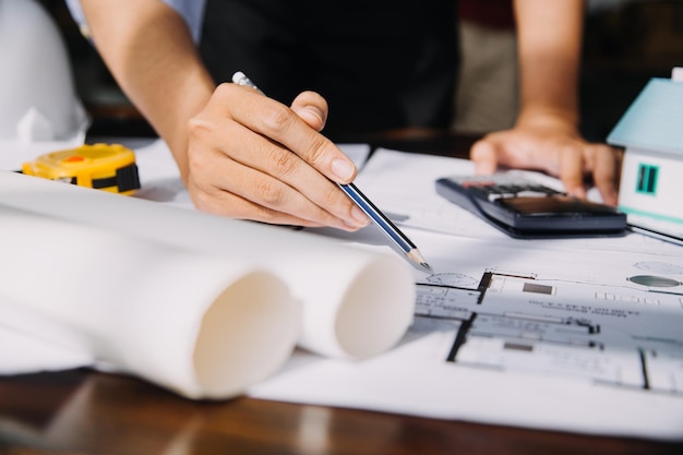 Dois especialistas inspecionam o projeto imobiliário do canteiro de obras do edifício industrial comercial com o investidor do engenheiro civil usam o laptop no fundo guindaste arranha-céu estruturas de concreto cofragem