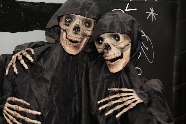 Foto dois esqueletos decorativos em capas de chuva pretas para halloween