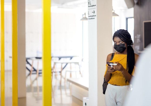 Dois estudantes africanos com máscara usando seus telefones celulares no campus