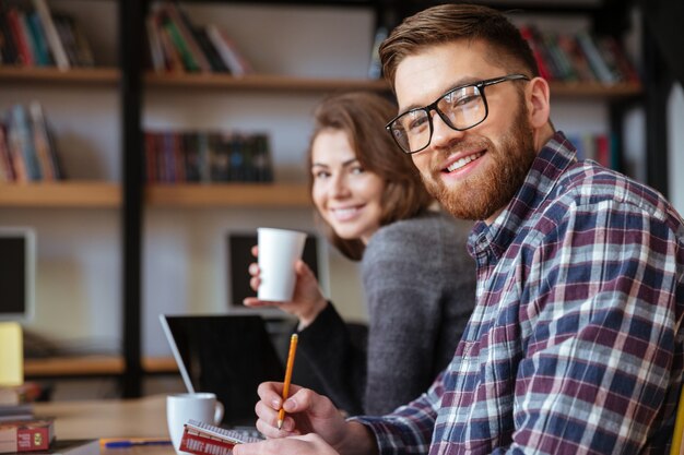 Dois estudantes felizes com redes de computadores laptop na biblioteca