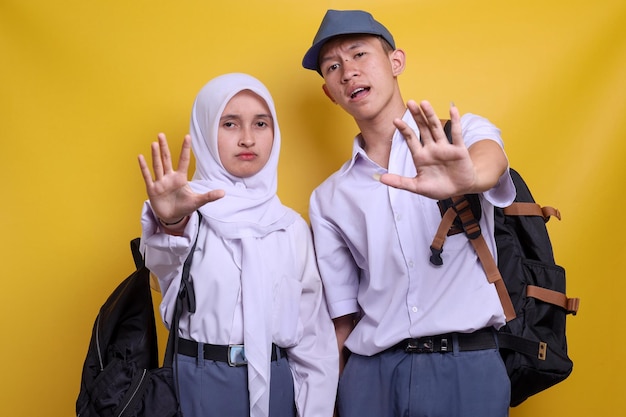 Dois estudantes indonésios do ensino médio vestindo uniforme mostrando a palma da mão dizendo pare e não façam nenhum gesto