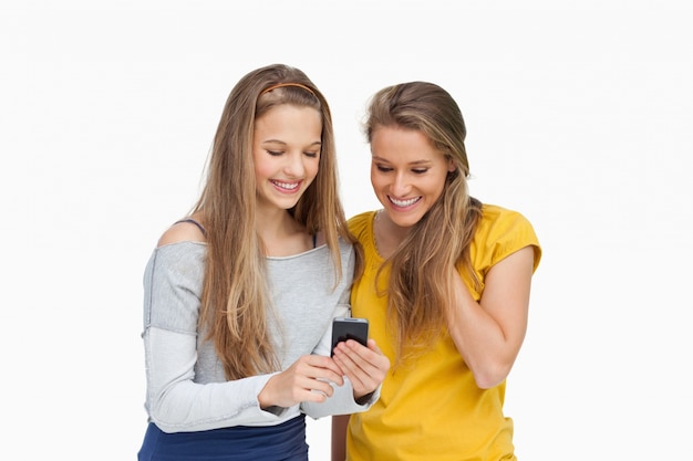 Dois estudantes sorridentes que procuram uma tela de celular