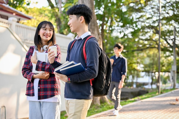 Dois estudantes universitários asiáticos conversando enquanto caminham pelo caminho do parque do campus