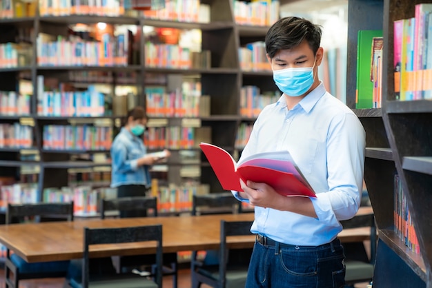 Dois estudantes universitários asiáticos usando máscara na biblioteca