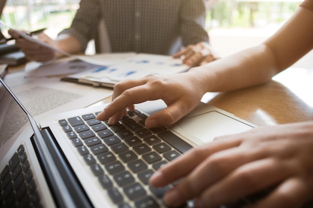 dois estudantes universitários que trabalham em conjunto com documentos de laptop e exames em um café / biblioteca