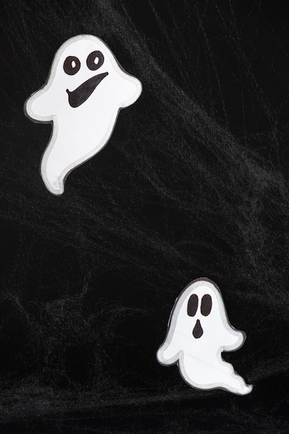 Dois fantasmas alegres com rostos voam e sorriem em um fundo preto com um cartão web de Halloween um lugar para texto