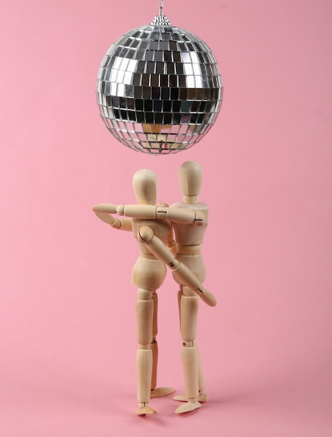 Dois fantoches dançando sob a bola de discoteca no conceito de festa de minimalismo de fundo rosa