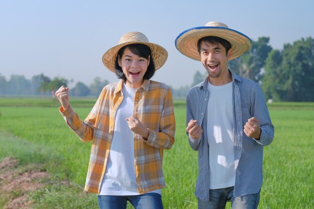 Dois fazendeiros asiáticos fazem uma cara surpresa e feliz em uma fazenda de arroz verde. conceito de alguns fazendeiros.