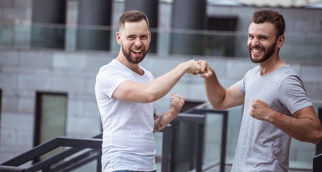 Dois felizes animados modernos barbudos melhores amigos em roupas casuais, se divertindo e conversando ao ar livre.