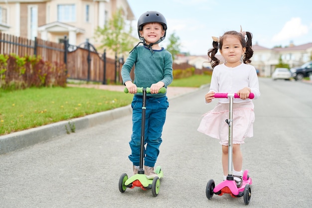 Dois filhos bonitos montando Scooters