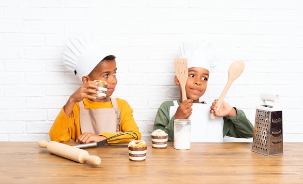 Dois filhos de irmãos afro-americanos vestidos como chef