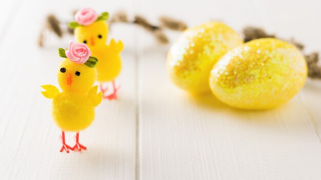 Foto dois filhotes de brinquedo e dois ovos de páscoa em uma mesa de madeira branca a decoração da mesa de páscoa.