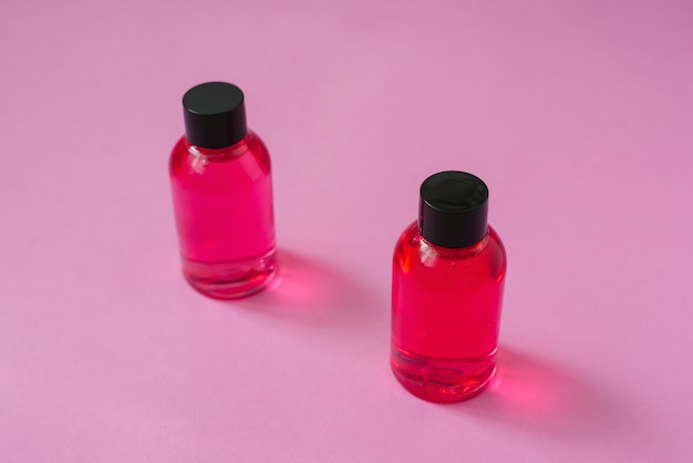 Dois frascos cor de rosa para cuidados com o corpo cosméticos, rosto ou cabelo em um fundo rosa. vista do topo