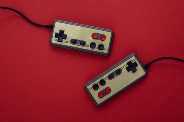 Dois gamepads retrô em fundo vermelho. Jogos, competição de videogame. Vista do topo